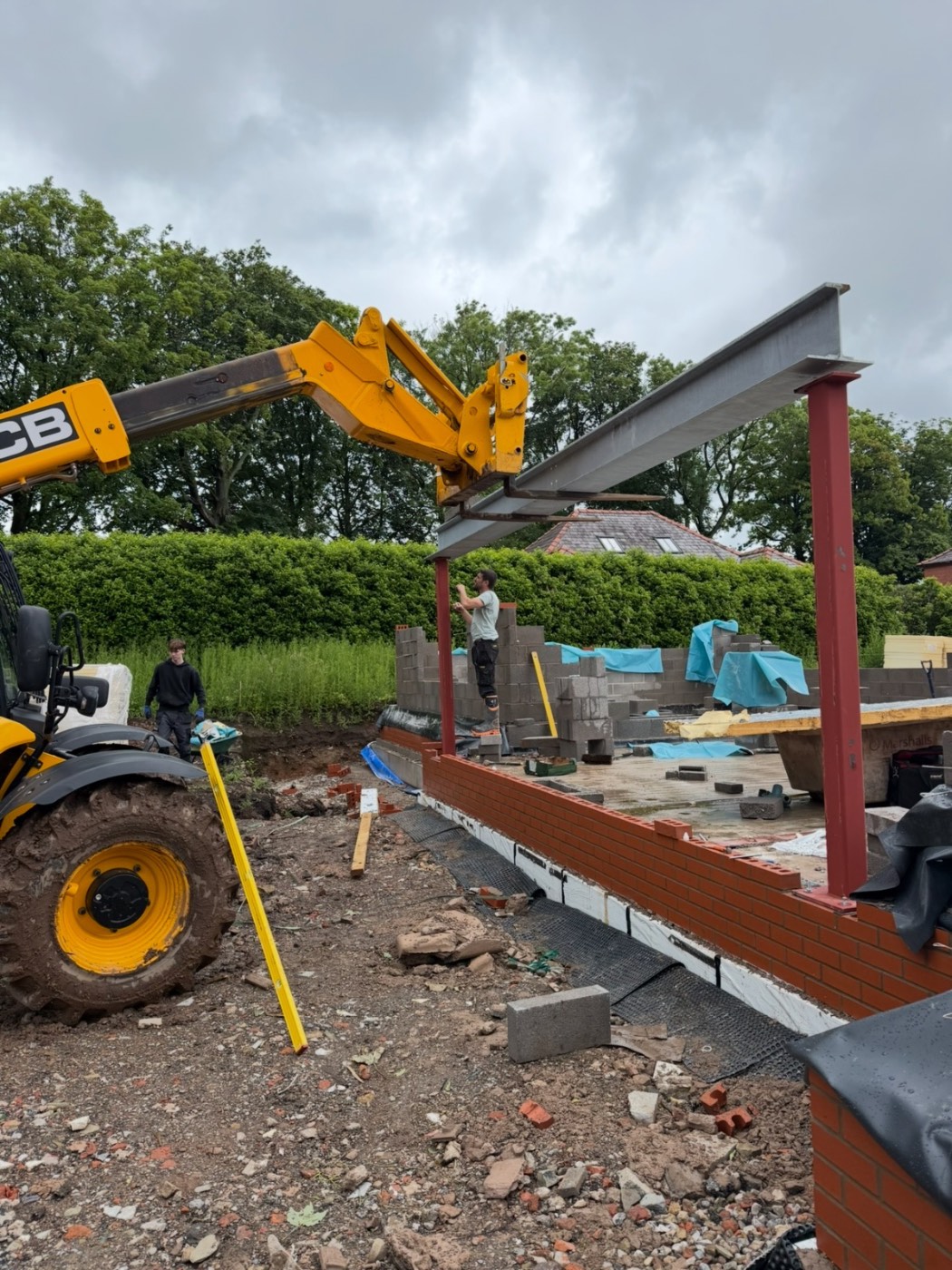 Structural steel beam being lifted into a property by a crane