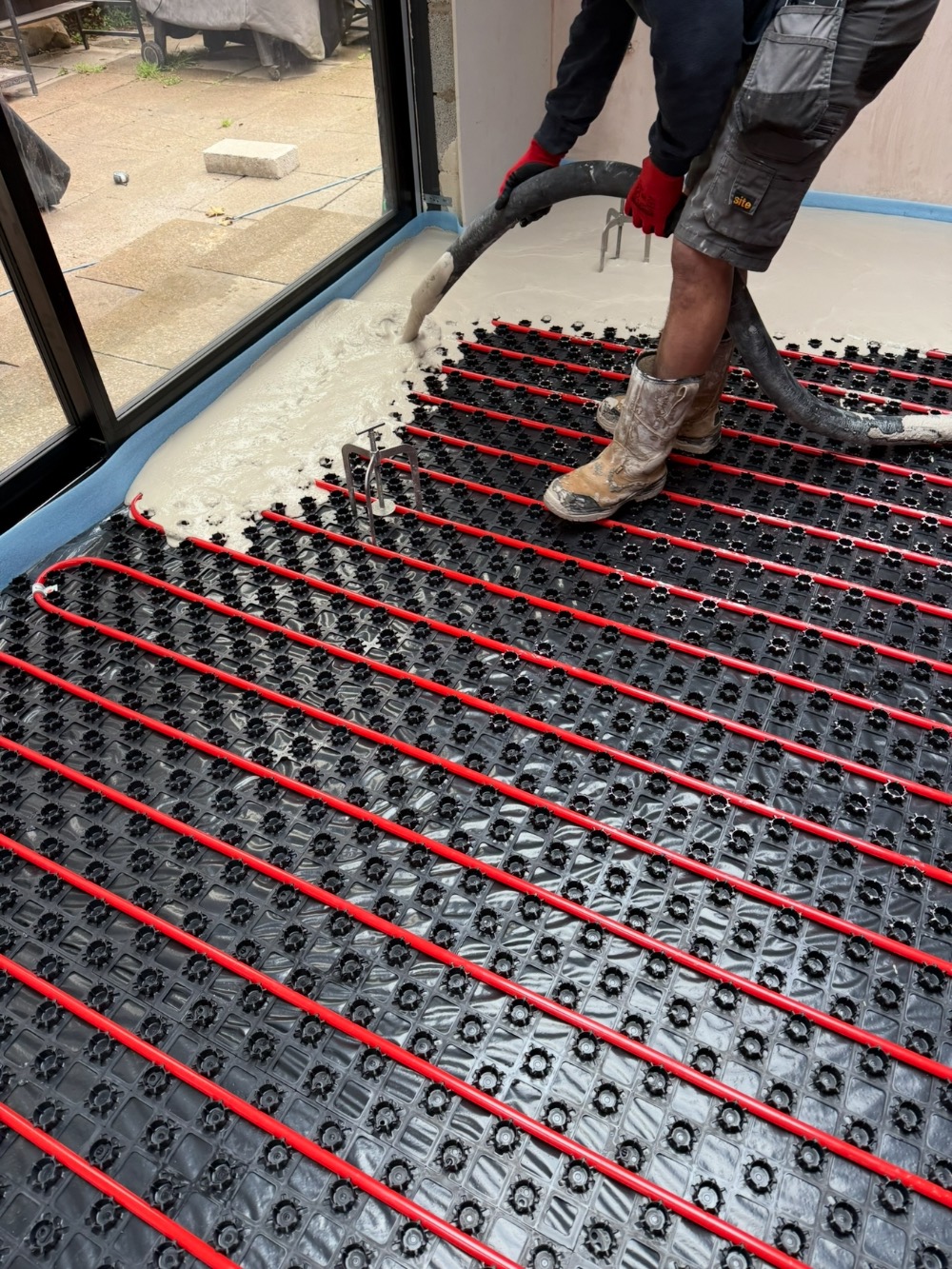 Liquid screed being poured over underfloor heating